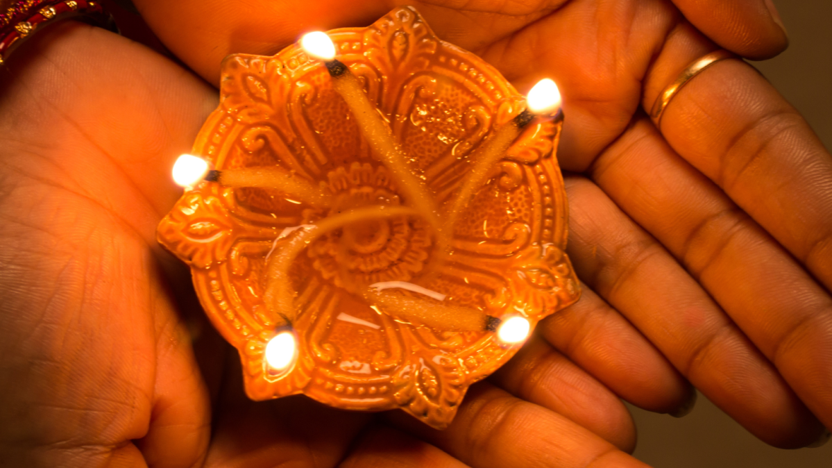 Hands holding a lit diya.