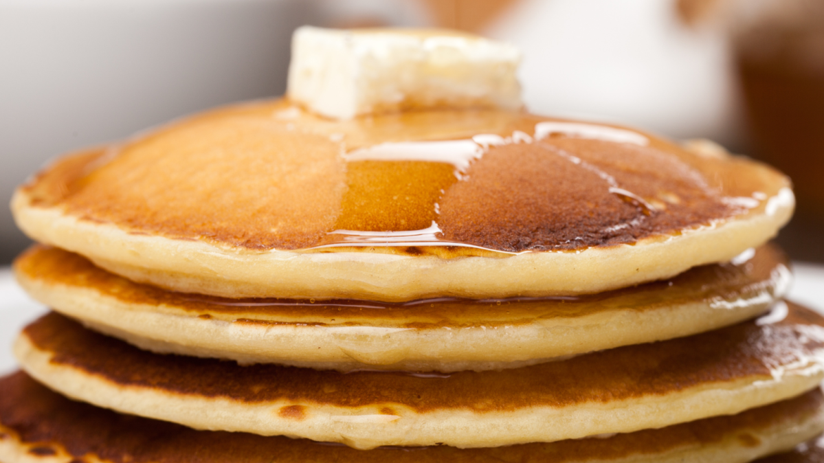 A stack of pancakes with butter and syrup.