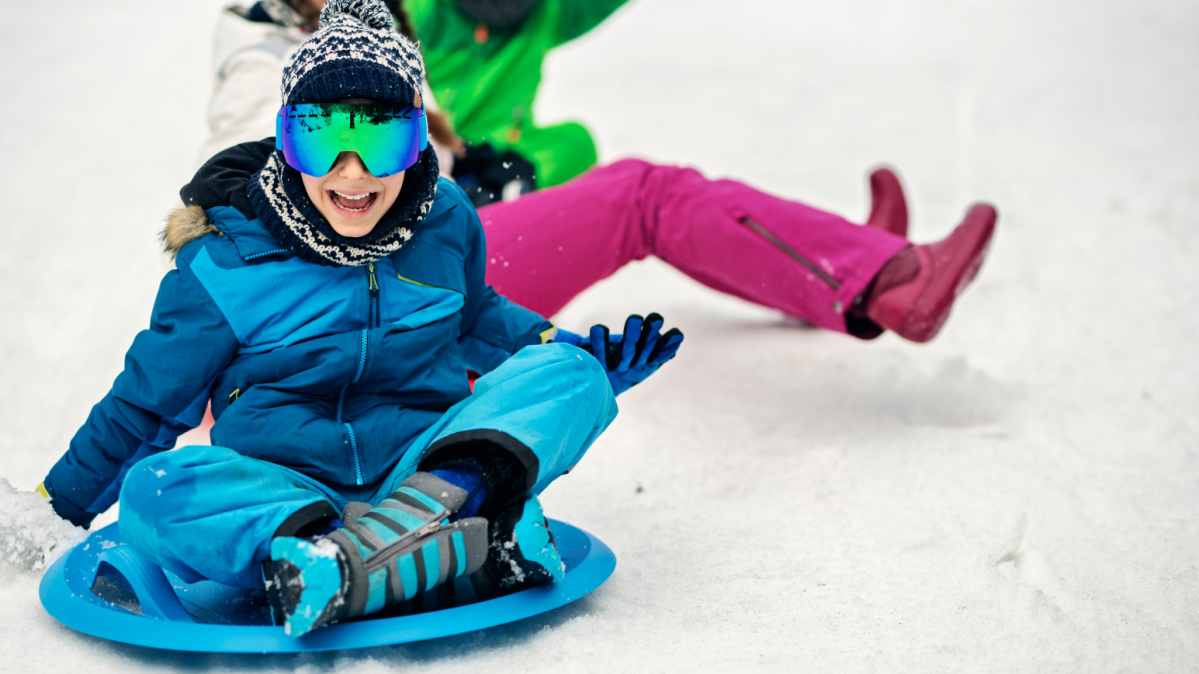 Kids sledding down a snowy hill.