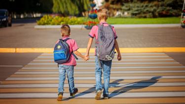 Two brothers crossing the street at a crosswalk.