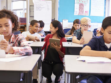 Teacher working with students at their desks.