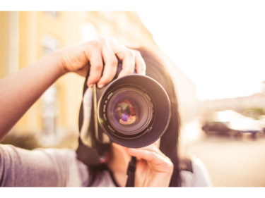 A person holding a camera in front of their face, taking a picture.