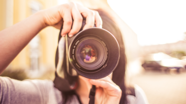 A person holding a camera in front of their face, taking a picture.