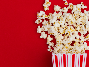 Popcorn spilling out of a red and white striped bag.