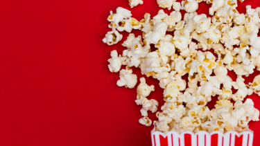 Popcorn spilling out of a red and white striped bag.