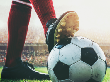 A soccer player's foot on top of a soccer ball.