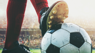 A soccer player's foot on top of a soccer ball.
