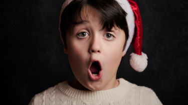 A student in a Santa hat singing.