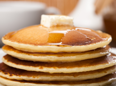 A stack of pancakes with butter and syrup.