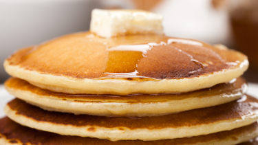 A stack of pancakes with butter and syrup.