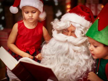 Two children reading with Santa Claus.