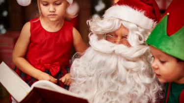 Two children reading with Santa Claus.