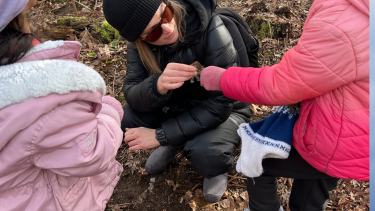 A teacher making a discovery with students in the forest.