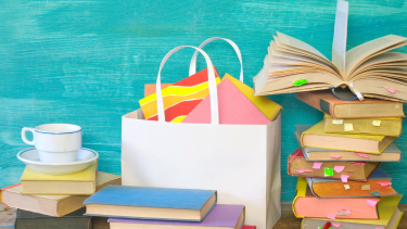 Books, a shopping bag and a coffee cup with a blue background. Scholastic Book Fair