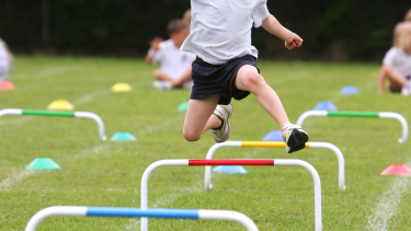 Sports Day Student running and jumping over hurdles.