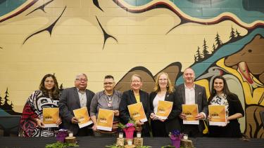 Group of Leaders from local First Nations, Metis community and district representatives, hold up their signed copies of the new enhancement agreement