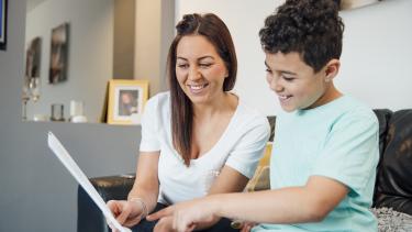 Elem/Middle Report Card Review A boy and his mother are looking at the child's report card together at home.