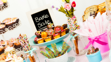 Bake sale items on a table with a sign.