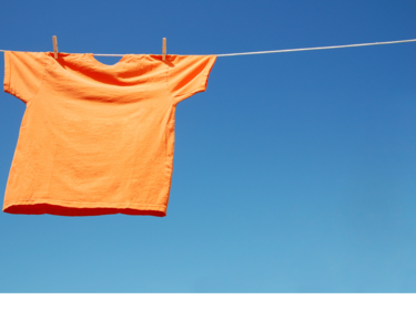An orange t-shirt hanging on a clothesline on a blue sky background.