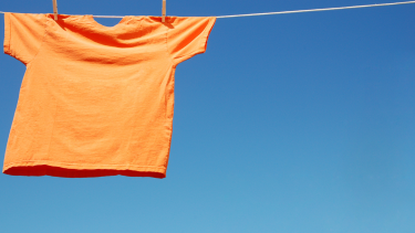 Orange Shirt Day An orange t-shirt hanging on a clothesline on a blue sky background.