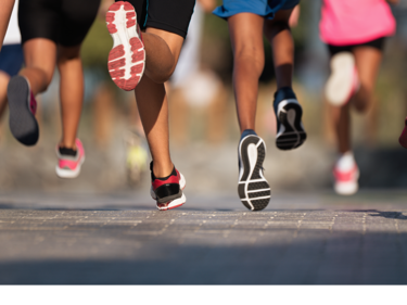 Legs of people running on a sunny day on concrete.