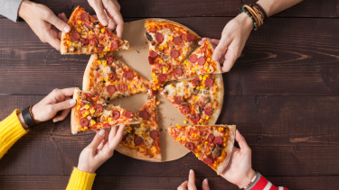 Children reaching for slices of pizza.