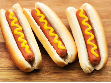 Three hot dogs with mustard on them.