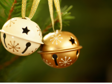 Gold and cream-coloured jingle bells hanging on a Christmas tree.