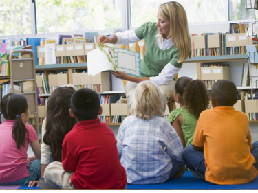 Students listening to a teacher reading them a story.