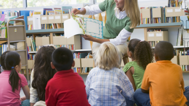 Students listening to a teacher reading them a story.