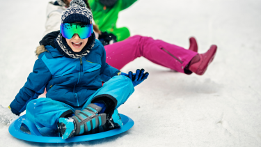 Kids sledding down a snowy hill.