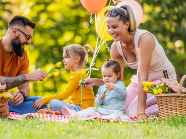 A family sitting on the grass having a picnic.