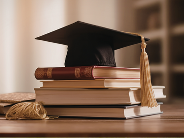 A graduation cap stacked on top of some books.