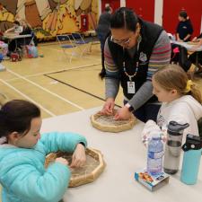 A female ISW helps two female grade 5 students with their drums