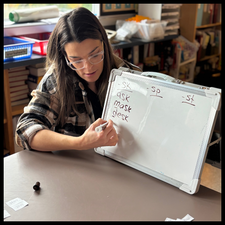 A teacher writing words on a white board.