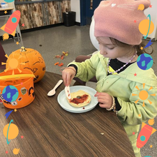 A student spreading jam onto a bagel.