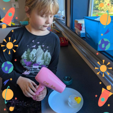 A student melting ice with a hair dryer to reveal a rubber ducky .