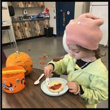 A student spreading jam on a bagel.