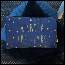 A blue pillow that says "wander the stars".