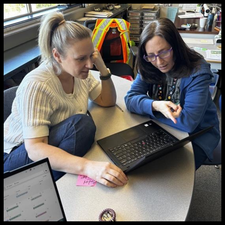 Two teachers talking at a table.